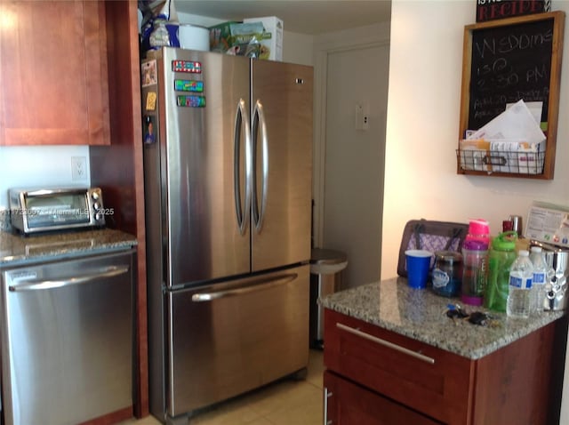 kitchen featuring stainless steel appliances, stone countertops, and light tile patterned flooring