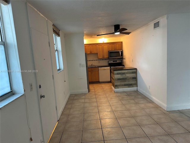 kitchen with backsplash, stainless steel appliances, ceiling fan, a textured ceiling, and light tile patterned flooring