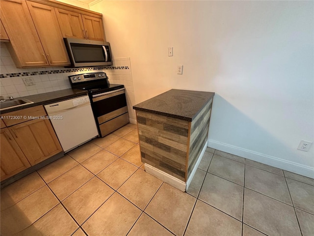 kitchen with sink, decorative backsplash, light tile patterned floors, and appliances with stainless steel finishes