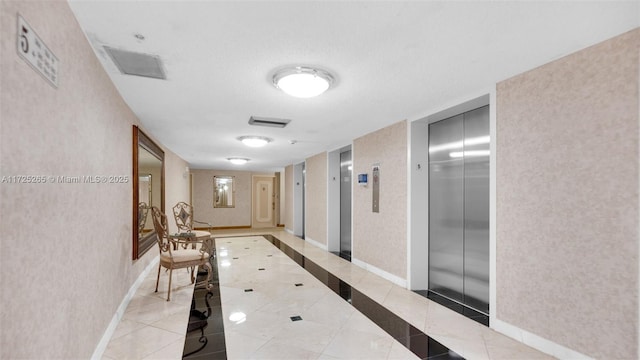 hall with elevator, a textured ceiling, and light tile patterned floors