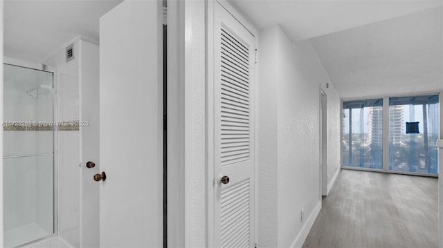 hall featuring light hardwood / wood-style floors and a wall of windows