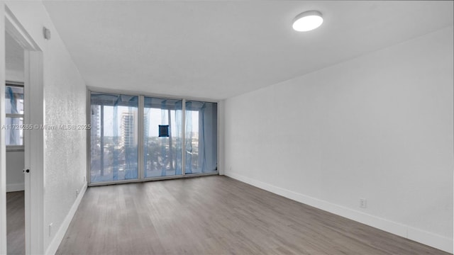 spare room with a wall of windows and hardwood / wood-style floors