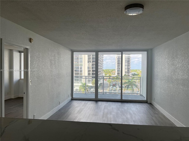 empty room with hardwood / wood-style flooring, a wealth of natural light, and floor to ceiling windows