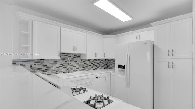 kitchen with sink, white cabinets, light stone counters, and white refrigerator with ice dispenser