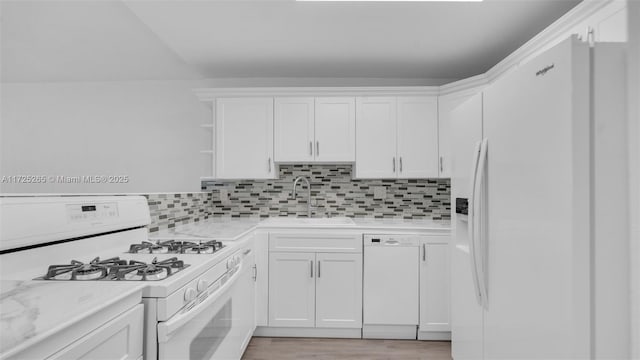 kitchen with white appliances, light stone counters, decorative backsplash, white cabinetry, and sink