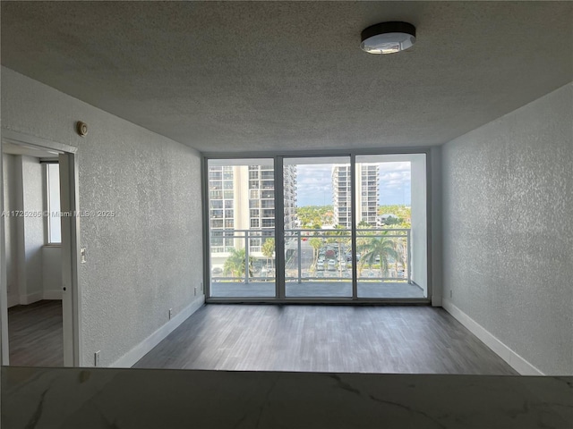 unfurnished room featuring a wall of windows and hardwood / wood-style floors