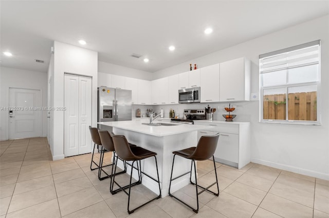 kitchen featuring sink, stainless steel appliances, white cabinets, and a kitchen island with sink