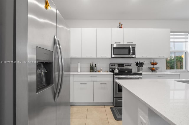 kitchen featuring light stone counters, stainless steel appliances, light tile patterned flooring, and white cabinets