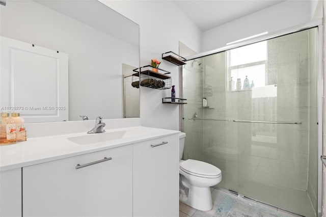 bathroom with toilet, vanity, and a shower with shower door