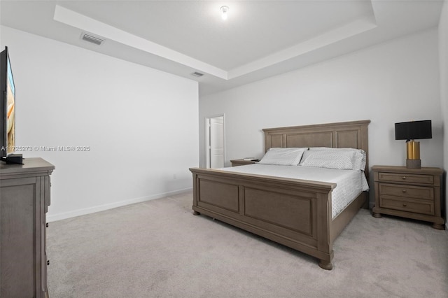 bedroom with light carpet and a tray ceiling