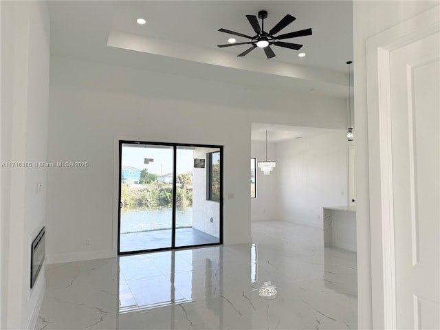 spare room with ceiling fan and a tray ceiling