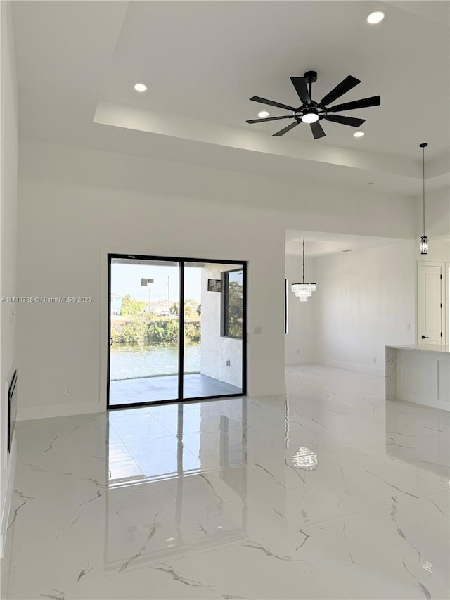 empty room with ceiling fan and a tray ceiling