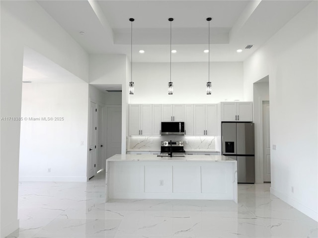 kitchen with a high ceiling, stainless steel appliances, white cabinets, and hanging light fixtures