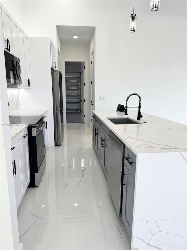 kitchen featuring stainless steel appliances, white cabinetry, pendant lighting, and sink