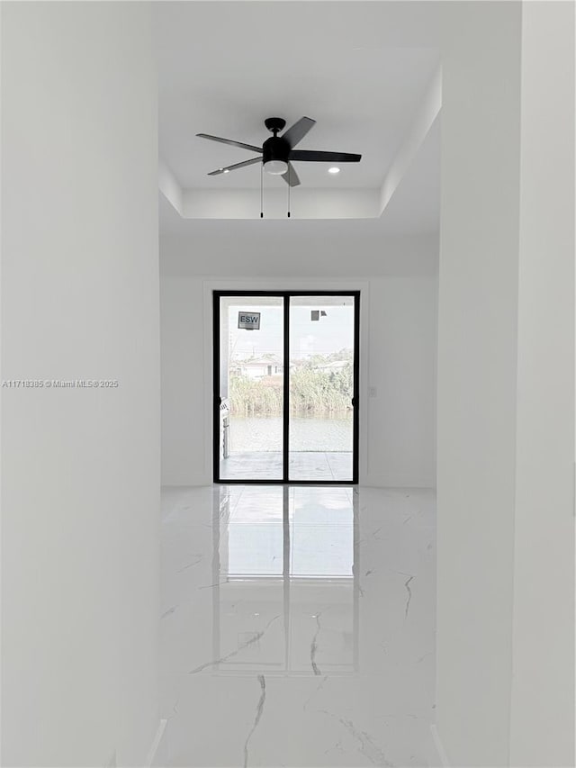 spare room with a raised ceiling and ceiling fan