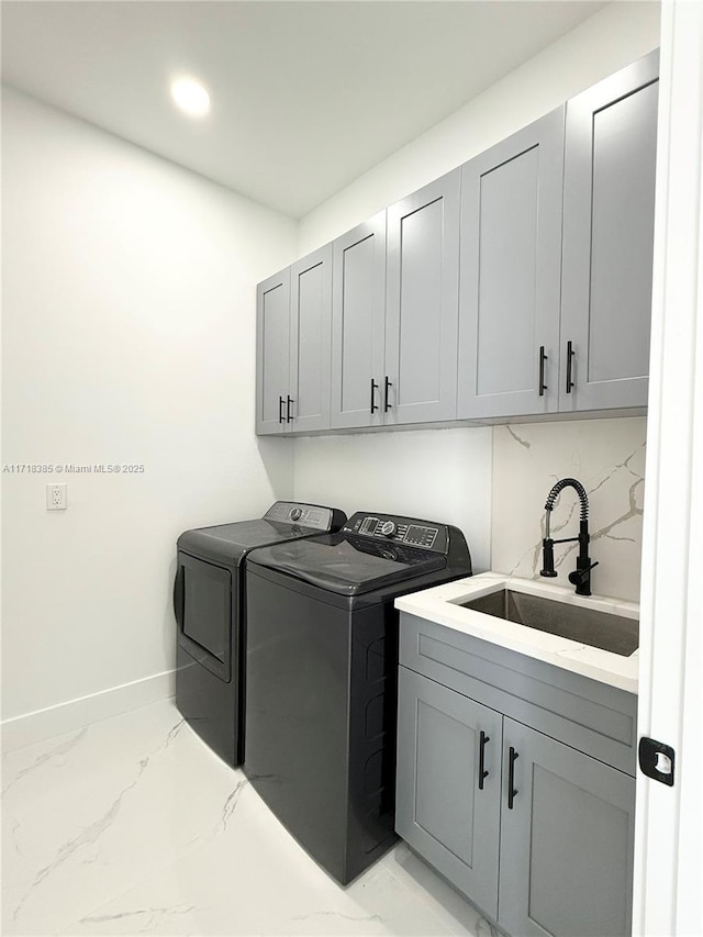 clothes washing area with sink, separate washer and dryer, and cabinets