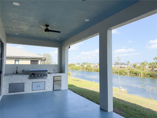 view of patio with grilling area, a water view, ceiling fan, area for grilling, and sink