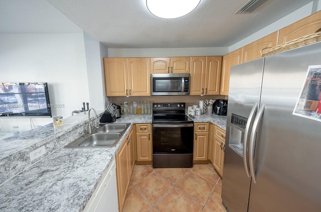 kitchen featuring a textured ceiling, stainless steel appliances, light brown cabinetry, light tile patterned floors, and sink