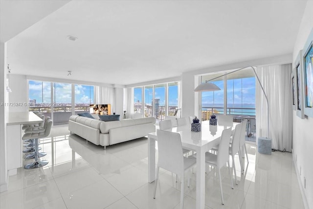 dining area featuring a water view, light tile patterned flooring, and expansive windows