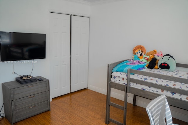 bedroom with a closet, crown molding, and hardwood / wood-style floors