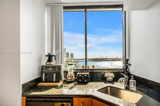 kitchen featuring sink, dark stone countertops, a wealth of natural light, and a water view