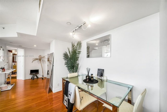 dining space with rail lighting and hardwood / wood-style flooring