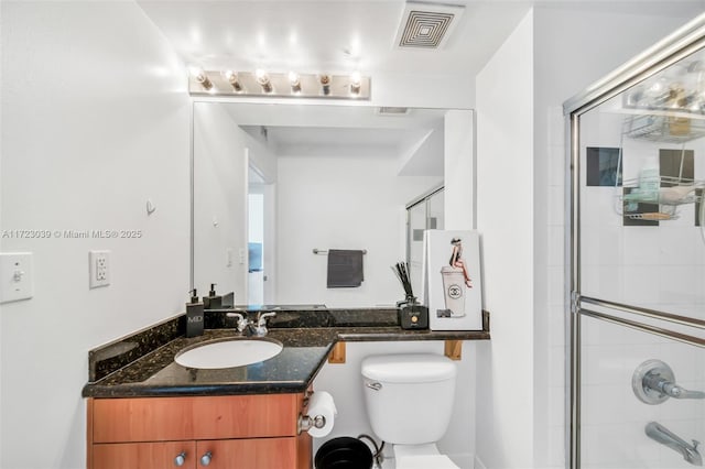 bathroom featuring toilet, a shower with door, and vanity