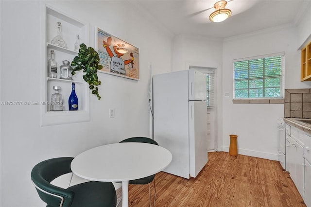 dining room with crown molding and light wood-type flooring