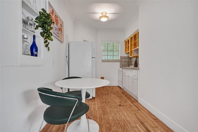 dining space featuring ornamental molding and light hardwood / wood-style floors