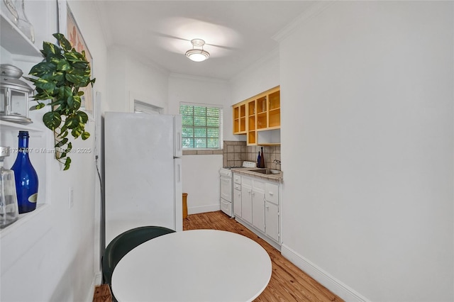 kitchen with crown molding, light hardwood / wood-style flooring, white appliances, decorative backsplash, and white cabinets