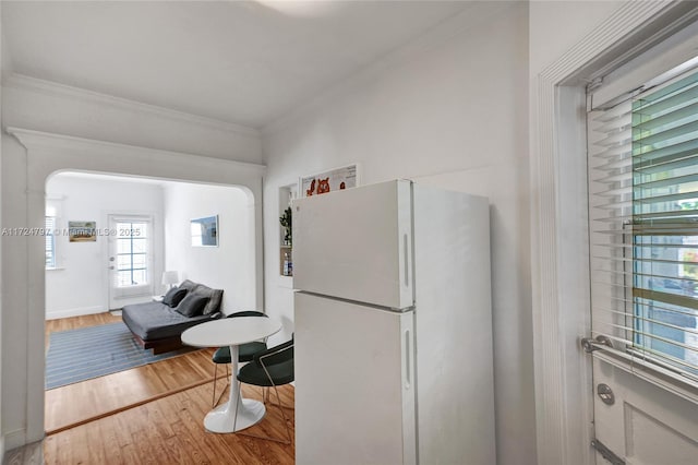 kitchen featuring ornamental molding, hardwood / wood-style floors, and white fridge