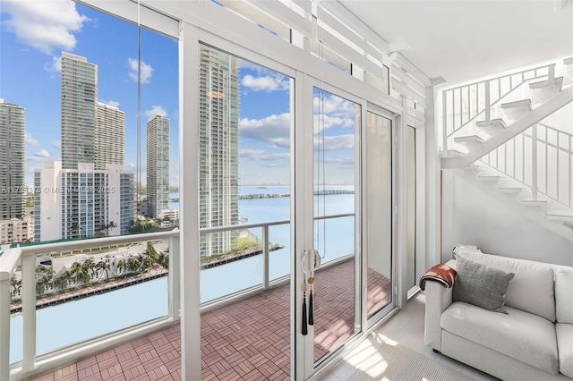 entryway with a water view, a view of city, stairs, and brick floor