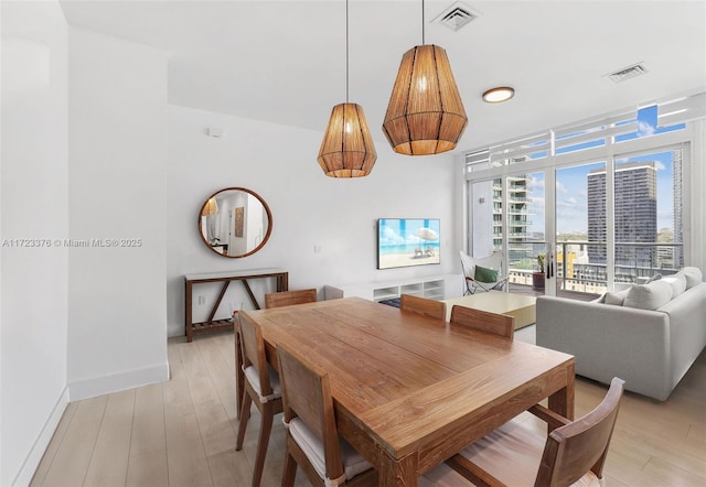 dining room with light wood finished floors, baseboards, expansive windows, and visible vents