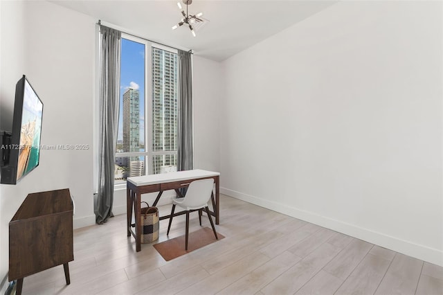 home office with expansive windows, light wood-type flooring, an inviting chandelier, and baseboards