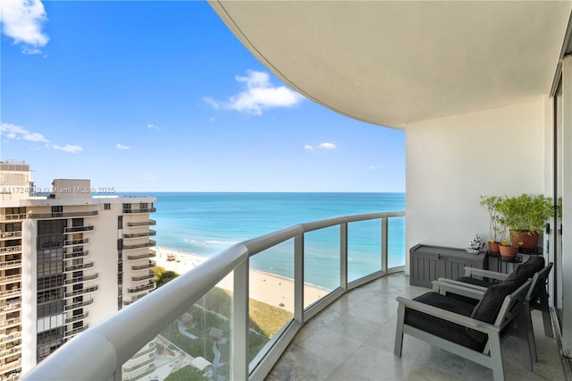 balcony featuring a view of the beach and a water view