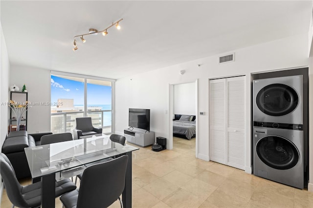 dining room featuring expansive windows, track lighting, visible vents, and stacked washer / drying machine