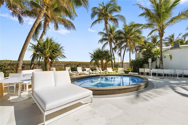 view of swimming pool with a jacuzzi, fence, and a patio area