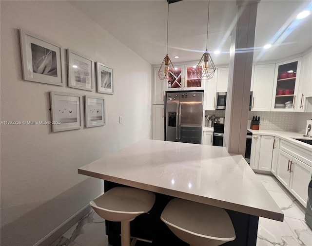 kitchen with a kitchen breakfast bar, stainless steel appliances, hanging light fixtures, decorative backsplash, and sink