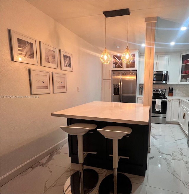 kitchen with stainless steel appliances, white cabinets, a kitchen breakfast bar, tasteful backsplash, and a kitchen island