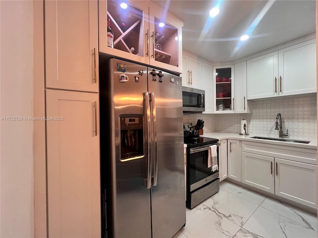 kitchen featuring stainless steel appliances, white cabinetry, backsplash, and sink