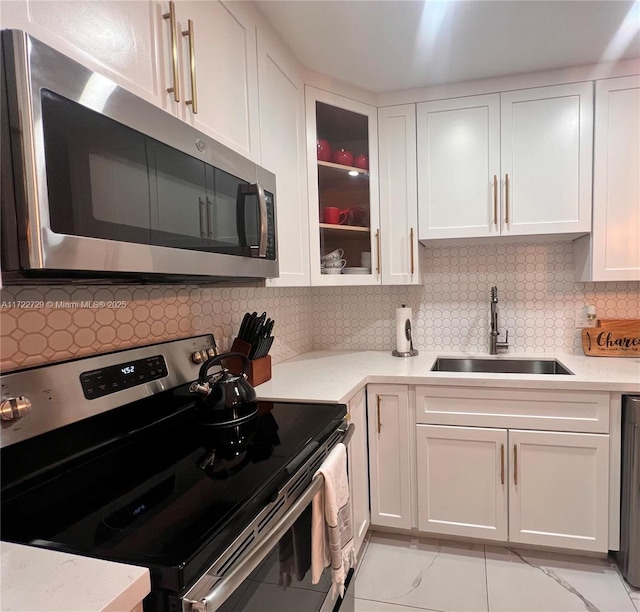 kitchen with stainless steel appliances, white cabinetry, decorative backsplash, and sink