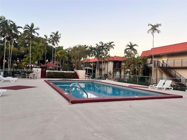 pool at dusk featuring a patio