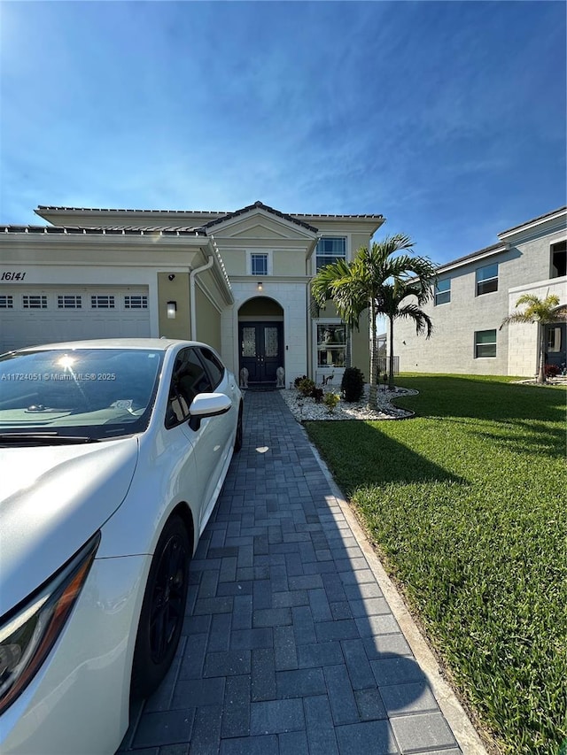 view of front of property featuring a garage, a front yard, and french doors