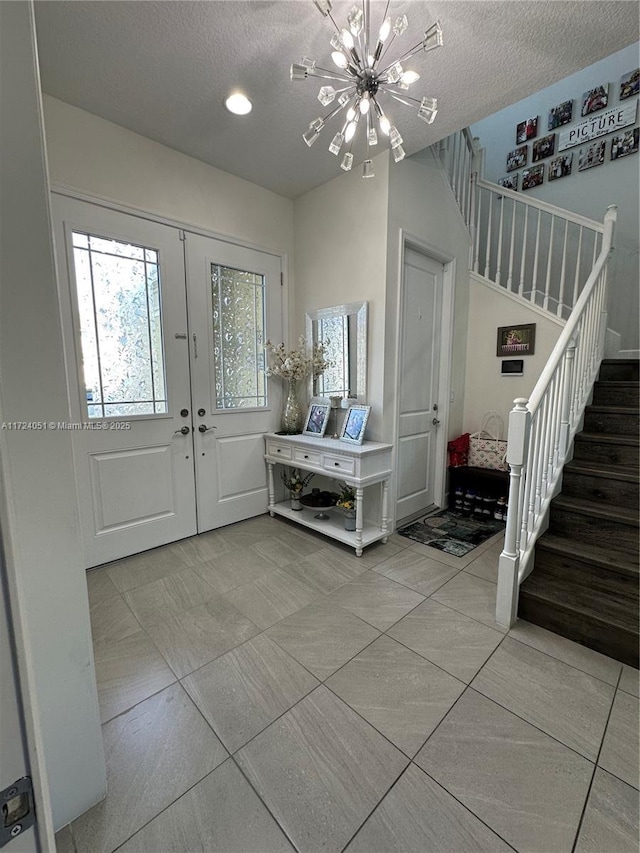 entryway with french doors, a textured ceiling, and a notable chandelier