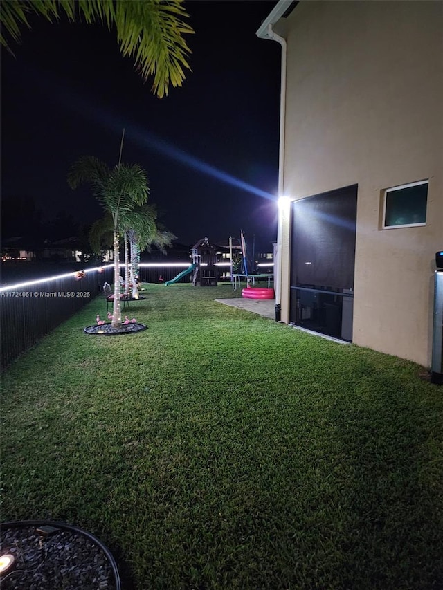 yard at night featuring a playground