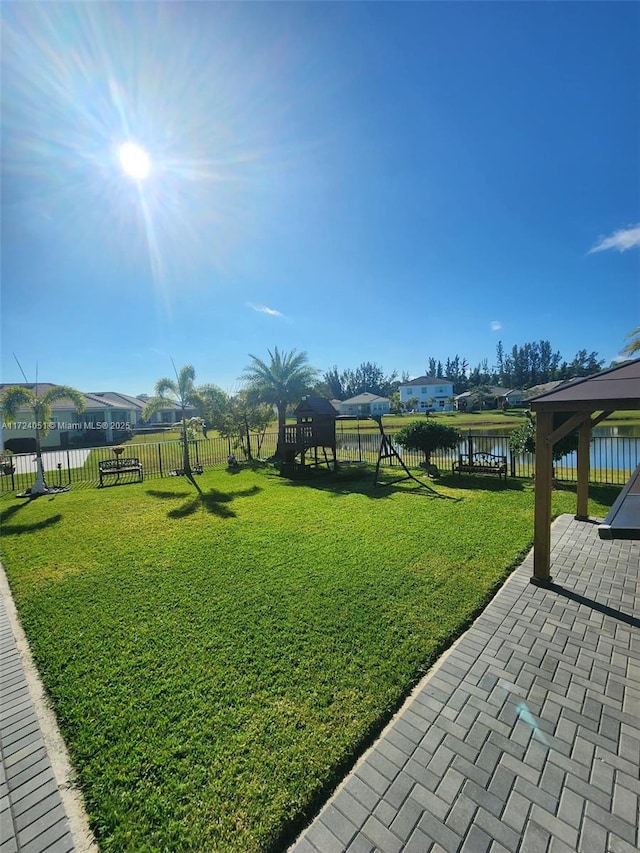 view of yard featuring a water view, a playground, a patio area, and a gazebo