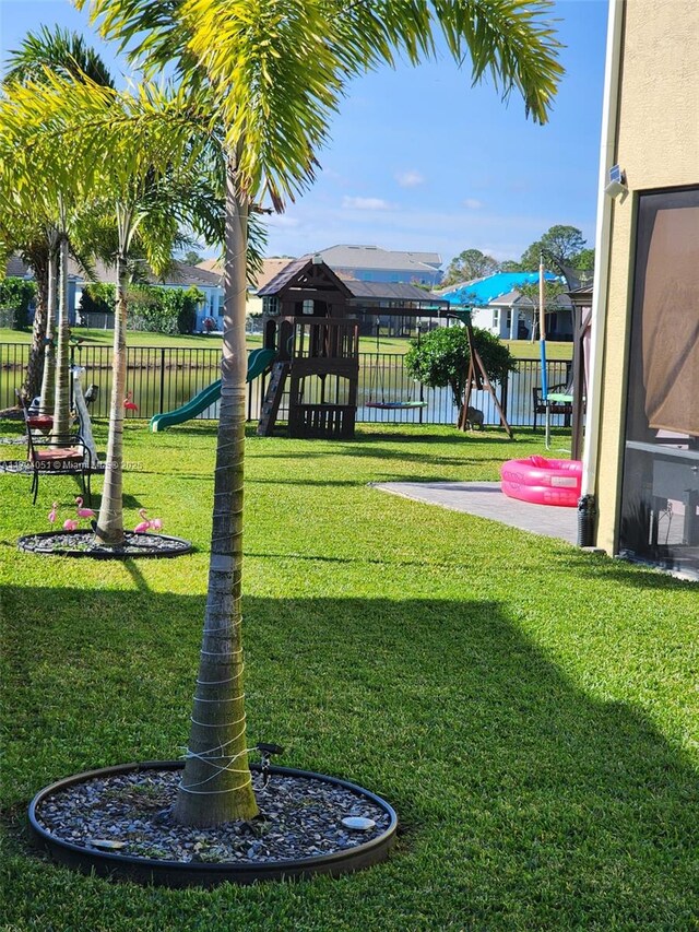 view of jungle gym featuring a lawn and a water view