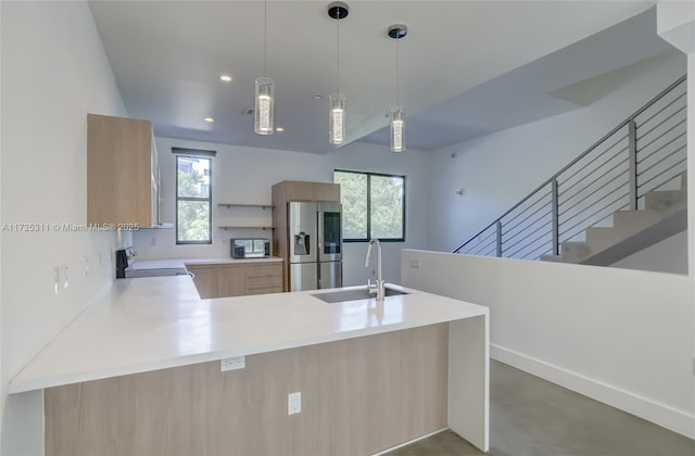 kitchen featuring sink, stove, stainless steel refrigerator with ice dispenser, kitchen peninsula, and light brown cabinets