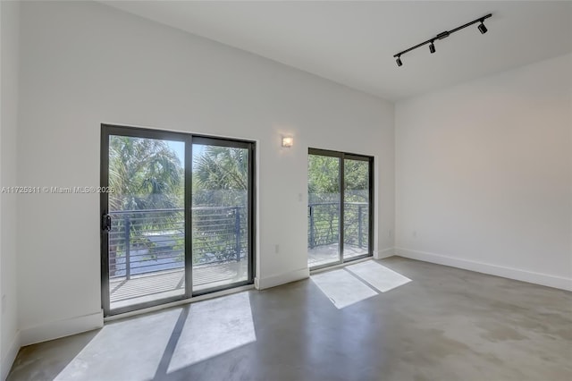 spare room with track lighting and concrete floors