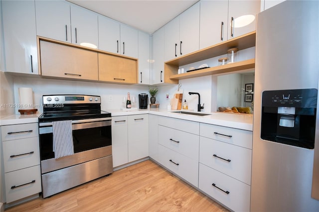 kitchen featuring sink, stainless steel appliances, light hardwood / wood-style floors, and white cabinetry